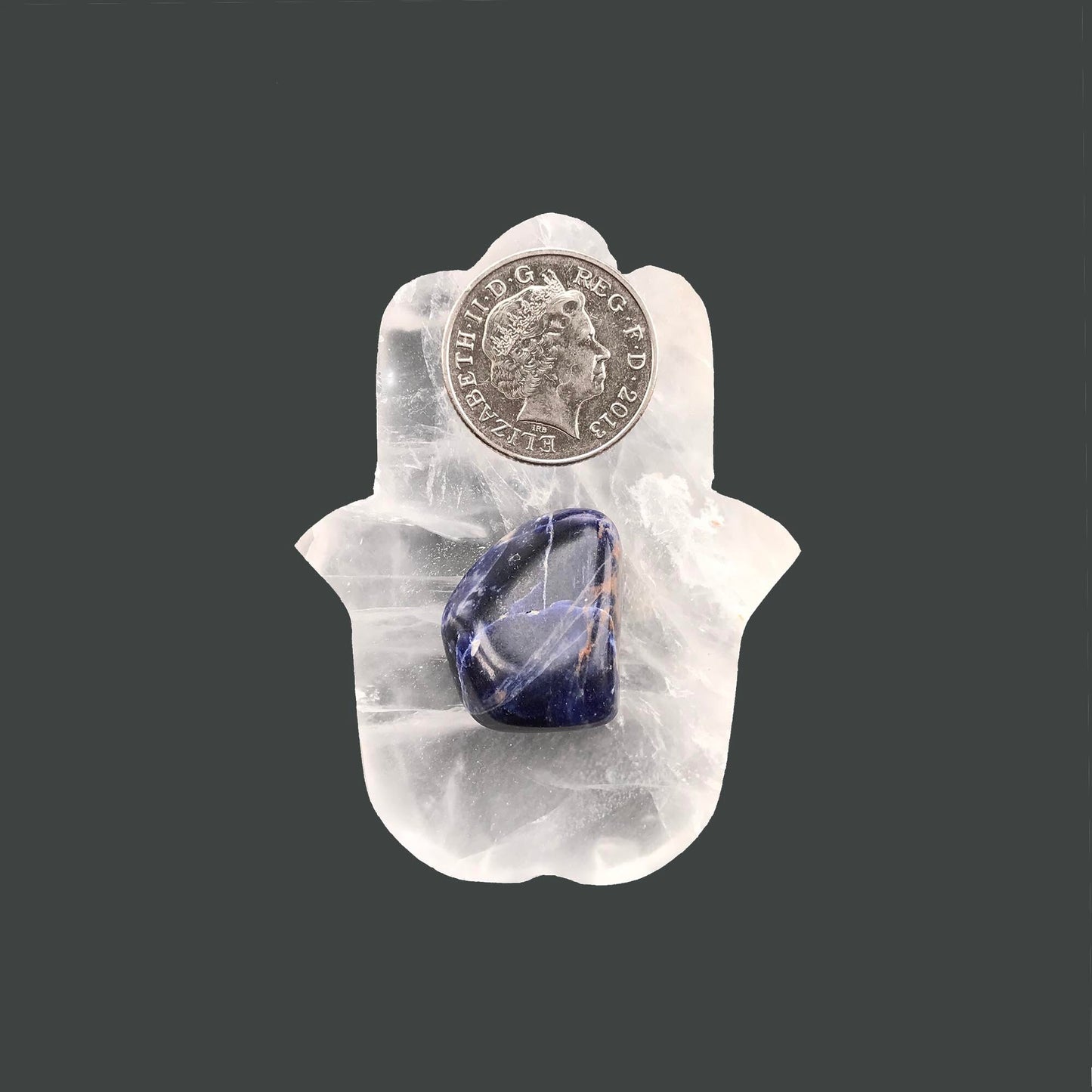 sodalite crystal on a selenite hamsa hand with 10 pence pence for scale