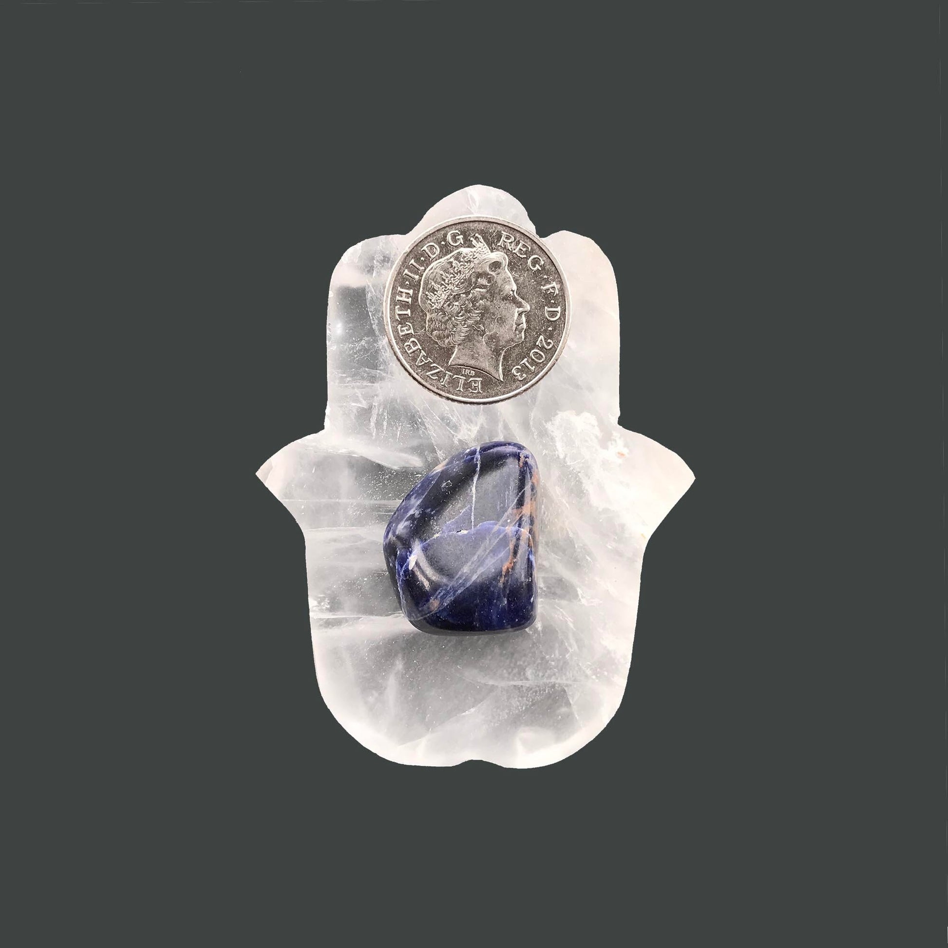 sodalite crystal on a selenite hamsa hand with 10 pence pence for scale